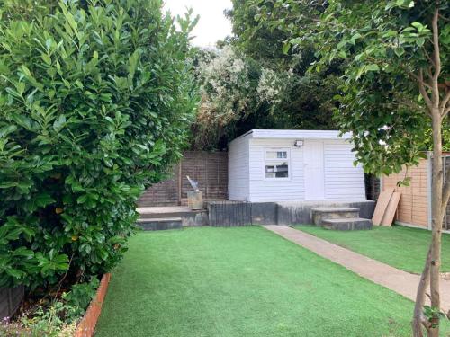 a garden with a white shed and a lawn at The AppleTree in West Drayton