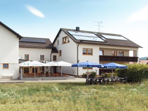 a building with tables and umbrellas in front of it at Landgasthof Benjamin in Treffelstein