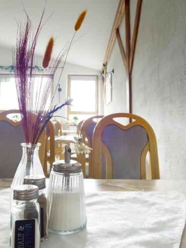 a table with a bottle of salt and a vase with flowers at Landgasthof Benjamin in Treffelstein