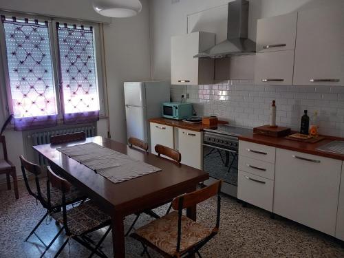 a kitchen with a wooden table and a kitchen with white cabinets at Ampio appartamento per 4/6 pers in Cesenatico