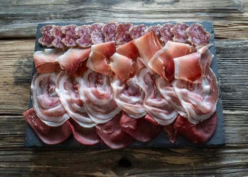 a cutting board with bacon and meat on a table at Albergo San Michele in Tirano