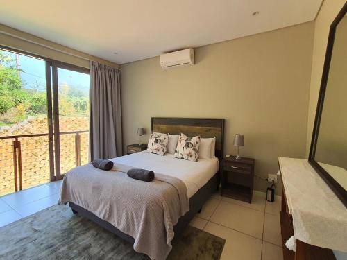 a bedroom with a bed and a balcony at Zimbali Wedge - Unit 29 in Ballito