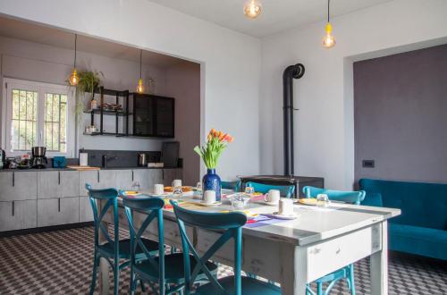 a kitchen with a table and blue chairs at Moncrivel Rooms & Relax in Benevello
