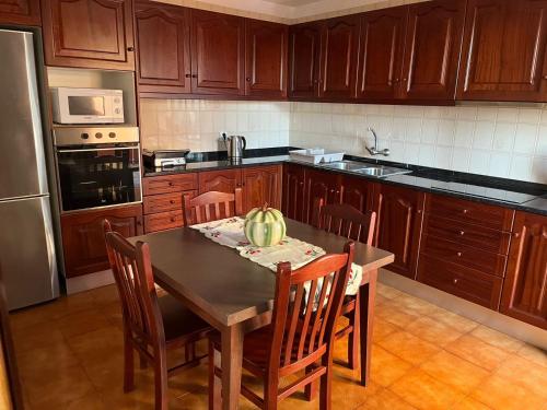 a kitchen with wooden cabinets and a table with chairs at Casa da Isilda ,three bedrooms in Estreito da Calheta