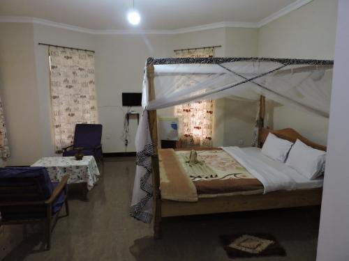 a bedroom with a canopy bed and a chair at Perigrin Rest House in Karatu