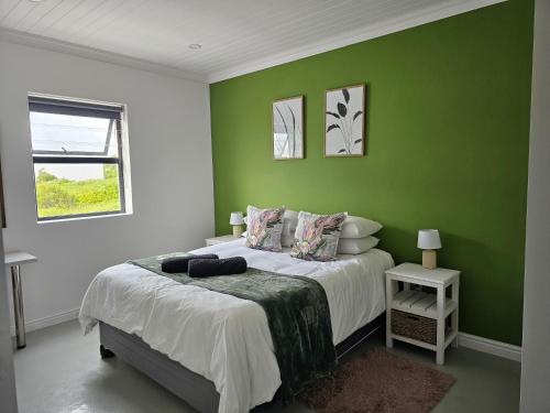 a green bedroom with a bed and a window at C-Rock Holiday Home Jacobs Bay in Jacobs Bay