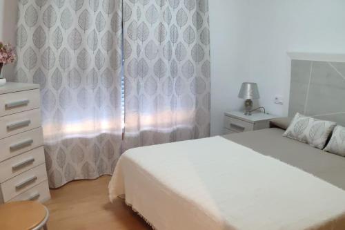 a bedroom with a white bed and a dresser and a window at A RIA DE PONTEVEDRA in Pontevedra