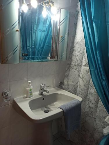 a bathroom sink with a mirror and a blue shower curtain at Fotini's Paradise in Platanidia