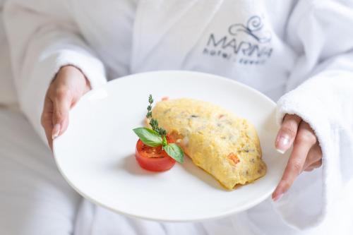 a person holding a white plate with a piece of food at Marina Hotel in Kuwait