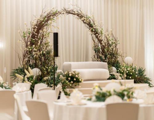 a table with white chairs and an arch with flowers at Marina Hotel in Kuwait