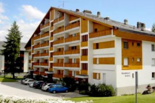 a large apartment building with cars parked in a parking lot at Appartement traversant secteur Violettes in Crans-Montana