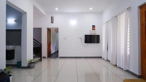 a hallway with white walls and white tile floors at WAYANAD OASIS VILLa in Kalpetta