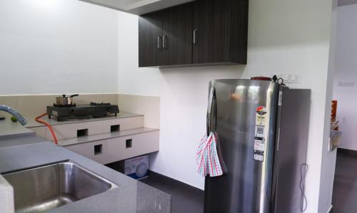 eine Küche mit einem Kühlschrank aus Edelstahl und einer Spüle in der Unterkunft WAYANAD OASIS VILLa in Kalpatta