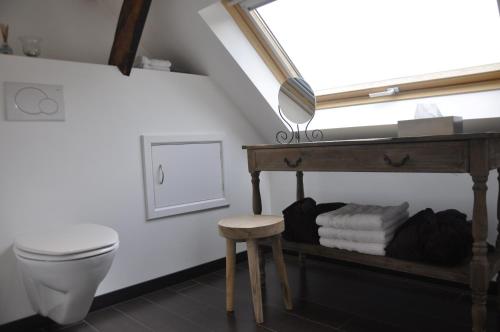 a bathroom with a toilet and a stool and a window at B&B De Paenhoeve in Eksel