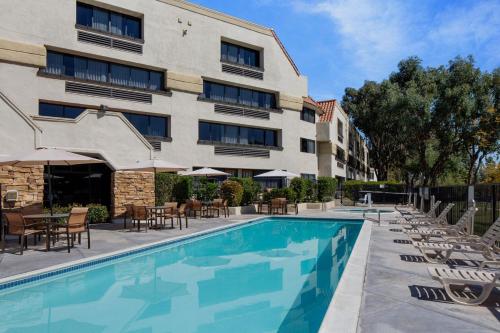 a hotel swimming pool with chairs and tables and a building at Courtyard by Marriott San Diego Rancho Bernardo in Rancho Bernardo