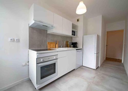 une cuisine avec des armoires blanches et un réfrigérateur blanc dans l'établissement appartement avec jaccuzzi 15 min du centre de lyon, à Villeurbanne