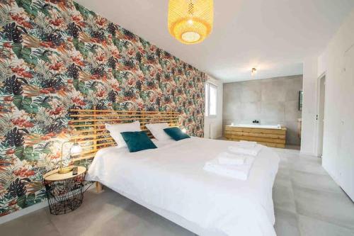 - une chambre avec un grand lit blanc et un papier peint floral dans l'établissement appartement avec jaccuzzi 15 min du centre de lyon, à Villeurbanne