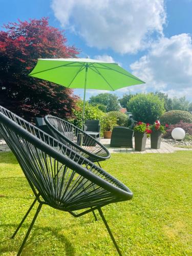 a green chair with a green umbrella on the grass at Landhaus Riedl in Bad Füssing