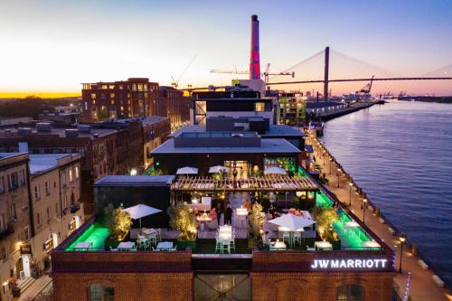 a restaurant on a building next to the water with a bridge at JW Marriott Savannah Plant Riverside District in Savannah