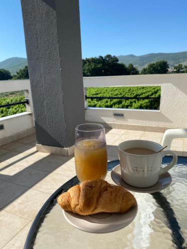 a table with a cup of orange juice and a croissant at Rooms Nikola Rule Ostojic in Međugorje