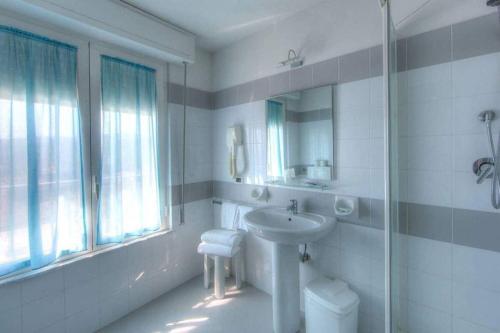 bagno bianco con lavandino e specchio di Hotel Mizar a Chianciano Terme