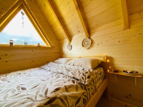 a bed in a log cabin with a window at Kapetanovo Jezero Bungalov in Podgorica