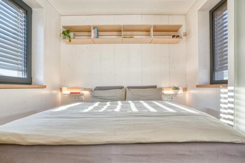 a large bed in a room with two windows at Tiny Design-Modulhaus mit 33 m² in Grimma