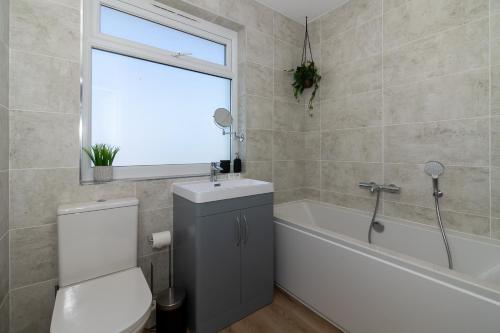 a bathroom with a toilet and a sink and a bath tub at 4 Bedroom House in Newquay