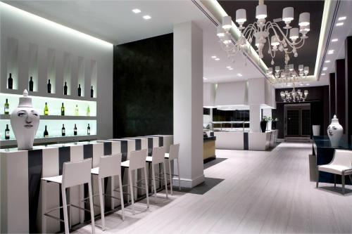 a restaurant with a bar with white chairs and a chandelier at Pelagos Suites Hotel & Spa in Kos Town