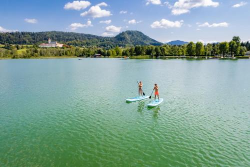 two people are standing on paddle boards on a lake at Romantisches Bergapartment - Luxus Studio auf der Simonhöhe in Zirkitz