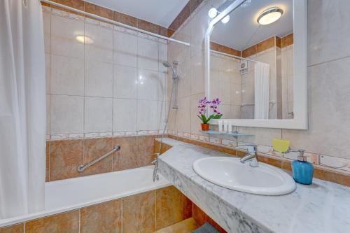 ein Badezimmer mit einem Waschbecken, einer Badewanne und einem Spiegel in der Unterkunft Apartment in Yucca park in Adeje