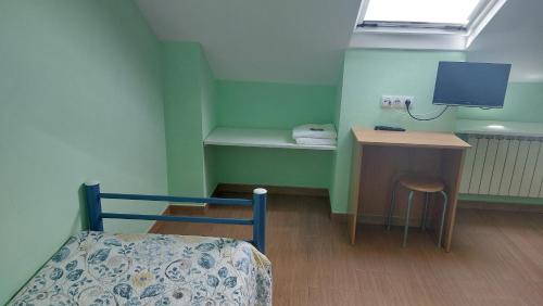a bedroom with a bed and a desk and a tv at Albergue la escuela in La Laguna