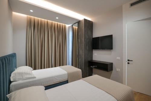 a hotel room with two beds and a television at DAED Luxury Residence in Sarandë