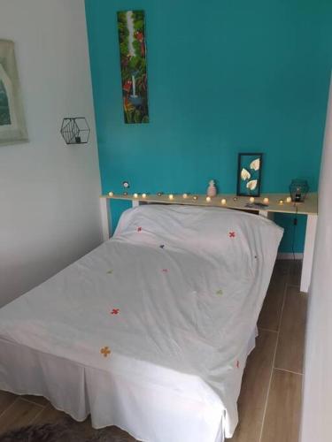 un lit dans une chambre avec un mur bleu dans l'établissement Maisonnette, à Biscarrosse