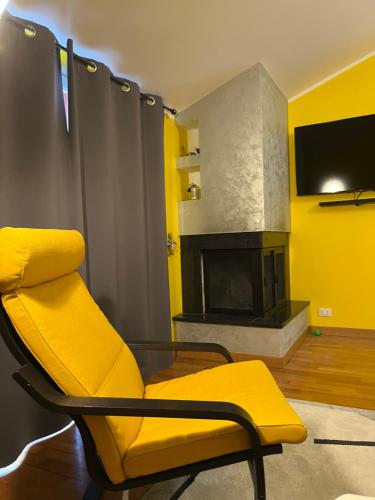 een gele woonkamer met een stoel en een open haard bij Yellow House in Teramo