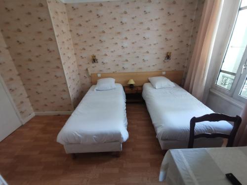 twee bedden in een kamer met twee stoelen en een tafel bij hotel le tourisme in Embrun
