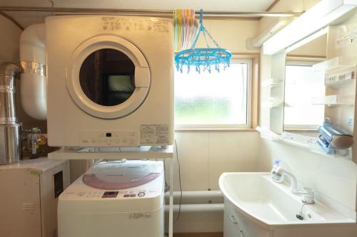 uma casa de banho com uma máquina de lavar roupa e um lavatório em Furano - House / Vacation STAY 56483 em Furano