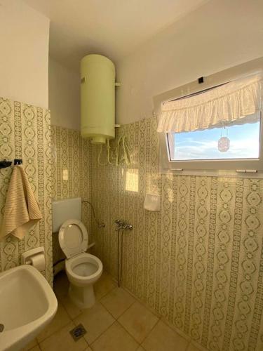 a bathroom with a toilet and a tub and a window at Blue Sky Apartment Paralia in Paralia Katerinis