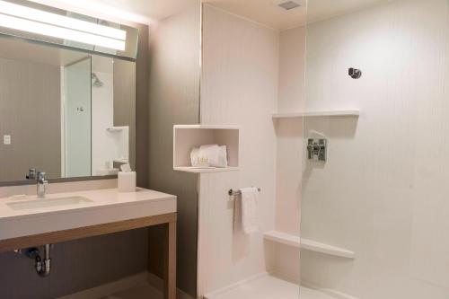 a bathroom with a sink and a shower with a mirror at Courtyard by Marriott Mt. Pleasant at Central Michigan University in Mount Pleasant