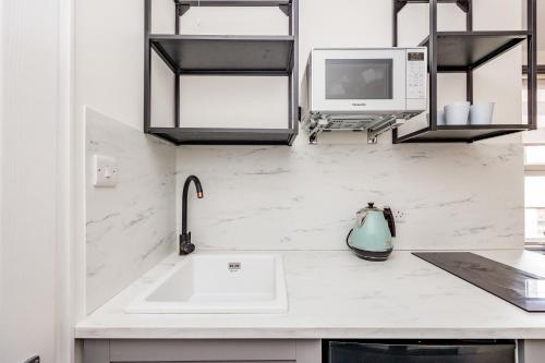 a white kitchen with a sink and a microwave at North Laine Boutique in Brighton & Hove