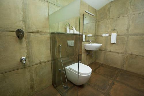 a bathroom with a shower and a toilet and a sink at Abad Brookside Wayanad in Vythiri