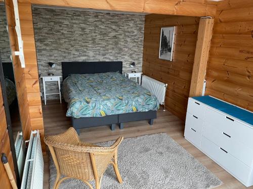 1 dormitorio con 1 cama y 1 silla en una habitación en Vrijstaande luxe Finse blokhut 2-6 of 2-8 pers, en Kropswolde