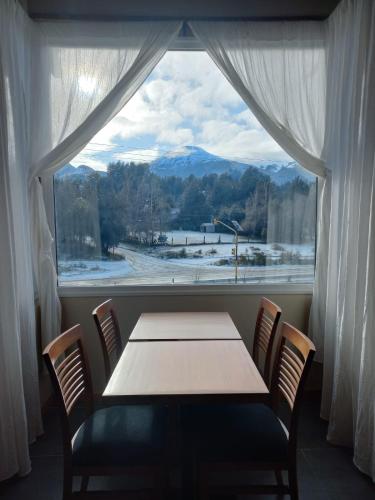 a table and chairs in front of a large window at Hostería Las Semillas in Villa La Angostura