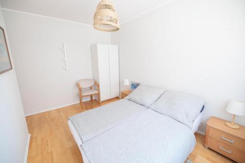 a white bedroom with a bed and a chair at APARTAMENTY BIAŁA MEWA - Na wydmie 8/9 in Ustka