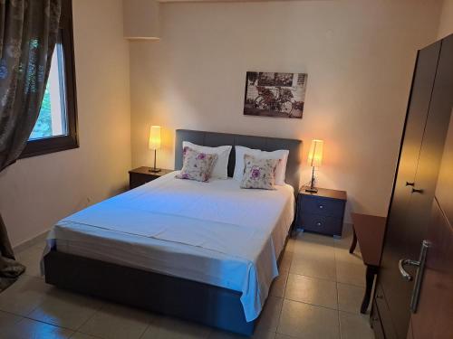 a bedroom with a large bed with two lamps at Nautica Bay Apartments in Keramoti