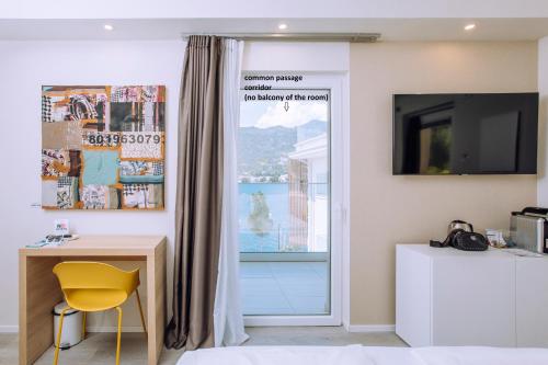 a room with a desk and a window with a yellow chair at Ah Porticcioli Boutique Apartments in San Felice del Benaco