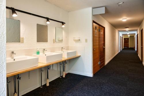 a bathroom with three sinks and two mirrors at Hütte Jil Shirakabako in Chino
