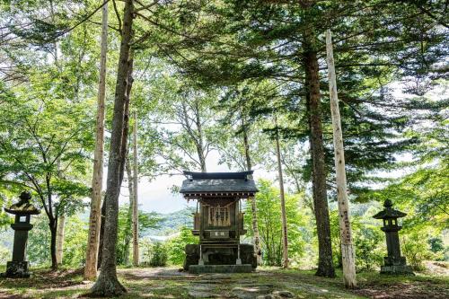 a small shrine in a forest with trees at Hütte Jil Shirakabako in Chino