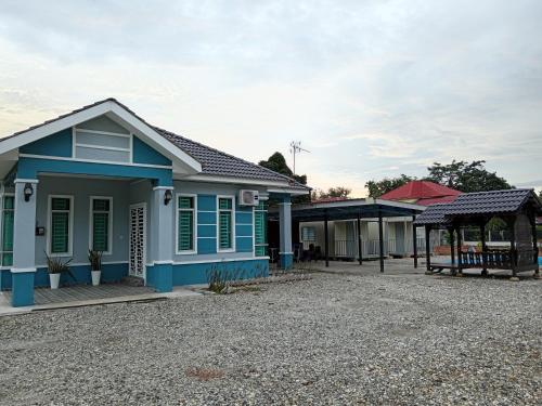 a house with blue and green trim on a gravel driveway at Homestay Pinang Tunggal in Sungai Petani