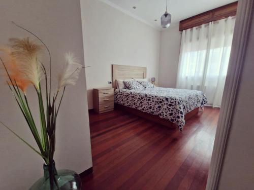 1 dormitorio con 1 cama y un jarrón con flores en MONFORTE CENTRO APARTAMENTO, en Monforte de Lemos